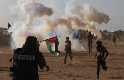 Manifestantes palestinos corren del gas lacrimógeno lanzado por los soldados israelíes, en la Franja de Gaza.  