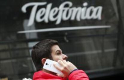 Un hombre habla por su m&oacute;vil ante la sede de Telef&oacute;nica en Madrid.