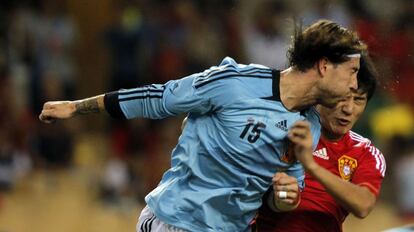 Sergio Ramos despega el balón de cabeza ante un jugador chino.