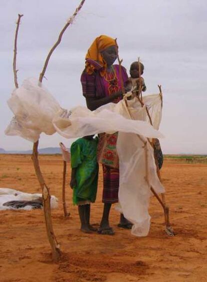 Hawa, refugiada en el campo de Abu Shouk, en Darfur, trata de recomponer el refugio de plástico deshecho por la lluvia.