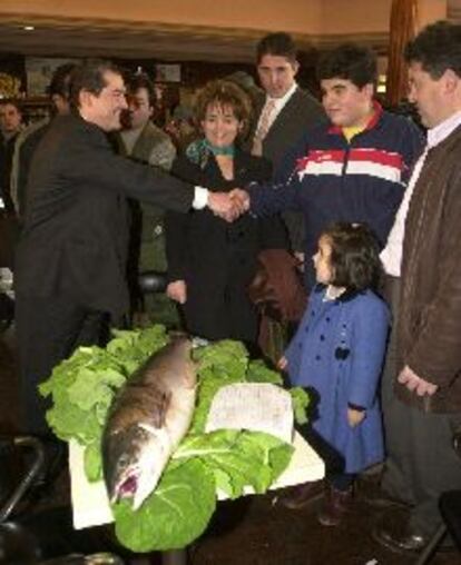 El joven Carlos Sepúlveda, rodeado de su familia, saluda al comprador de su salmón, el <i>campanu</i>, pescado ayer en el río Narcea.