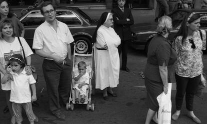 Una monja, de pie, entre el público al paso de la antorcha.