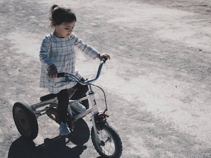 Una niña va con su tríciclo por la calle.