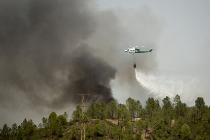 Un helicóptero suelta agua durante el incendio en la localidad onubense de Nerva.