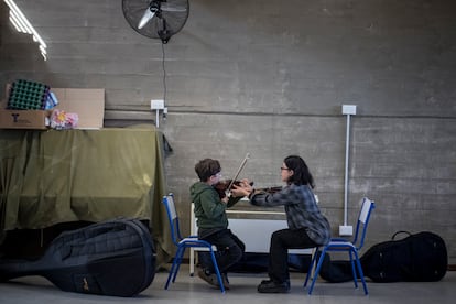 Una maestra supervisa la práctica de violín de uno de los niños de la orquesta, el pasado 24 de agosto.