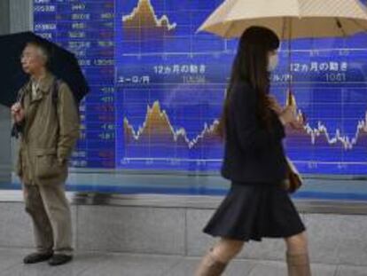 Una viandante pasa delante de una pantalla que muestra valores bursátiles en Tokio (Japón). EFE/Archivo