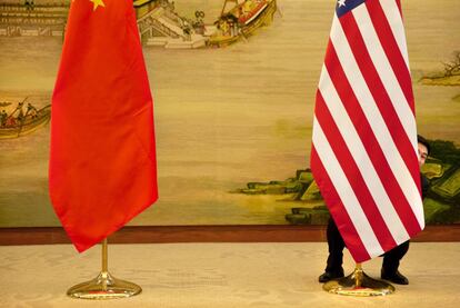 Un operario tras la bandera de Estados Unidos que ha sido colocada junto a la de China para recibir al secretario de Estado norteamericano, John Kerry.