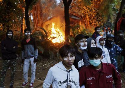 Manifestantes con pasta de dientes alrededor de los ojos para mitigar el efecto del gas lacrimógeno, junto a un fuego durante un enfrentamiento con la policía antidisturbios en Yakarta (Indonesia).