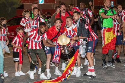 Los jugadores colchoneros sujetan el trofeo tras llegar a la ciudad de portiva del equipo en Majadahonda. 