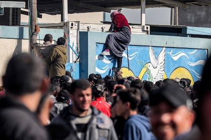 Una mujer trataba este martes de escalar un muro para acceder a un almacén de la agencia de la ONU para los refugiados palestinos (UNRWA), tras horas esperando en una cola en Rafah para recibir una ración de harina.