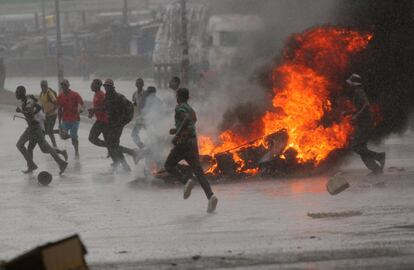 Un grupo de personas corre junto a una barricada en llamas durante la jornada de protestas en Harare.