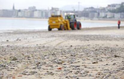 Una máquina despedregadora retira las piedras de la playa de Ondarreta.