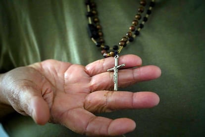 Caridad, una de las vecinas, muestra el rosario que lleva al cuello.