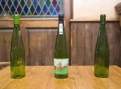 Una botella de <b><i>txakoli</b></i> Amestoi, en el centro, junto a dos sin etiqueta; en una de ellas en el corcho pone Amestoi.