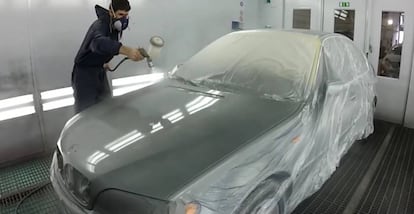 Un operario pintando un coche.