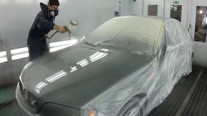 Un operario pintando un coche.