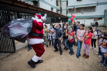 Un hombre vestido de Santa Claus reparte juguetes entre los niños, este viernes en Caracas (Venezuela).