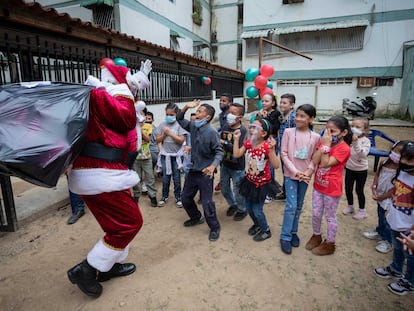 Un hombre vestido de Santa Claus reparte juguetes entre los niños, este viernes en Caracas (Venezuela).