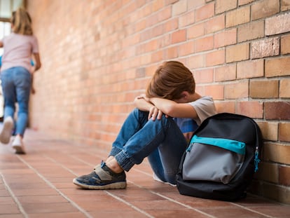 Un menor sentado en el suelo, tras ser víctima de un episodio de acoso escolar.