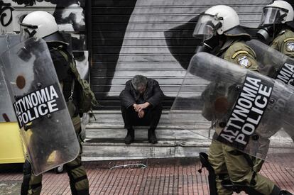 Un hombre sentado en las escaleras de una tienda cerrada durante la manifestación en el centro de Atenas.