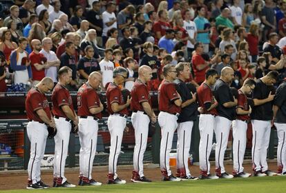 Jugadores y entrenadores del equipo de beisbol de Arizona Diamondbacks inclinan la cabeza durante un minuto de silencio por los muertos en Baton Rouge.