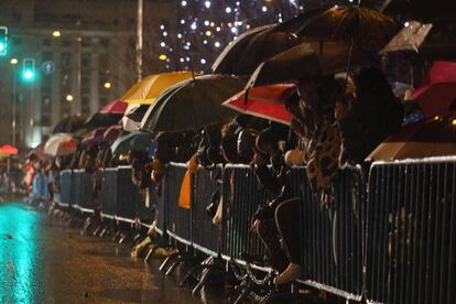 Niños esperan la llegada de los Reyes Magos en Madrid bajo la lluvia.