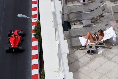Una mujer toma el sol en un balcón mientras el piloto de Fórmula 1 Sebastian Vettel, de Ferrari, participa en la primera sesión de entrenamientos libres para el Gran Premio de Mónaco de Fórmula 1.
