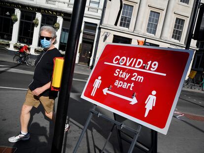 Un hombre camina junto a un cartel en Londres que pide que se mantengan dos metros de distancia entre personas.