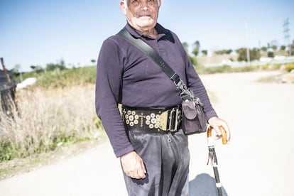 Jesús Hervás, vecino de Pan Bendito (Carabanchel), sale a caminar cada día por los alrededores del polígono Prado Overa. Para mantenerse erguido durante las caminatas, compró un cinturón que ha decorado con monedas antiguas y crucifijos. "Todos llevamos una cruz desde que nacemos", cuenta.