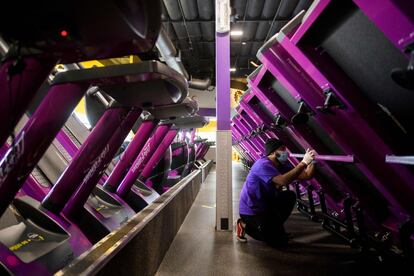 Un empleado de Planet Fitness Inc. limpia debajo de las cintas de correr en preparación a la reapertura de los gimnasios en Inglewood, California, este lunes.