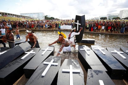 Varios indígenas entran al río frente al Congreso de Brasilia con ataúdes falsos.