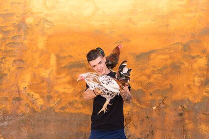 Un joven posa orgulloso con sus gallos.