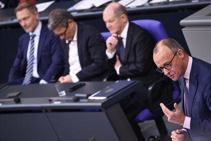 El líder de la oposición alemana, el conservador Friedrich Merz, durante su intervención este martes en el Bundestag, con el canciller Olaf Scholz y los ministros Robert Habeck (centro) y Christian Lindner escuchándole en sus escaños.