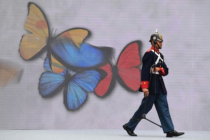 Un cadete colombiano pasa al lado de un mural de 3 mariposas pintadas con los colores de la bandera de Colombia, en Bogotá, el 7 de agosto de 2022.