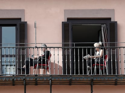Dos personas leen en el balcón de su domicilio tras el estado de alarma decretado en España.
