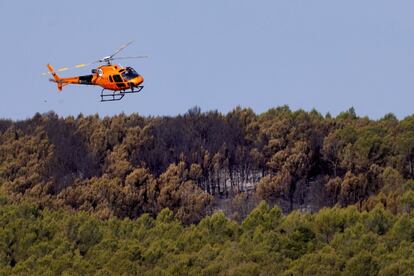 Un helicóptero sobrevuela este domingo un paraje forestal en la zona afectada por el incendio de Ventalló (Girona), este domingo.