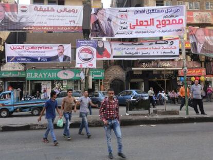 Varias personas caminan junto a pancartas electorales en Giza.