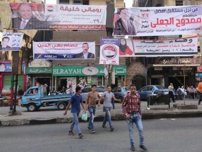 Varias personas caminan junto a pancartas electorales en Giza.