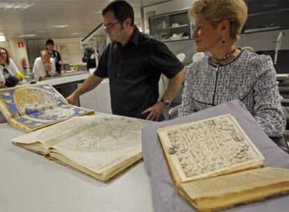 La directora de la Biblioteca Nacional, Milagros del Corral, y el encargado de restauración muestran algunas de las láminas recuperadas.