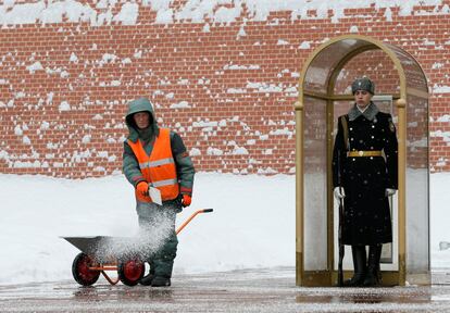 Un trabajador municipal arroja sal en el suelo frente a una guardia de honor en la Tumba del Soldado Desconocido junto al muro del Kremlin en el centro de Moscú (Rusia).