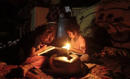 Dos niños palestinos hacen los deberes durante un apagón en Gaza.