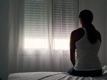 Una mujer observa la ventana desde su habitación