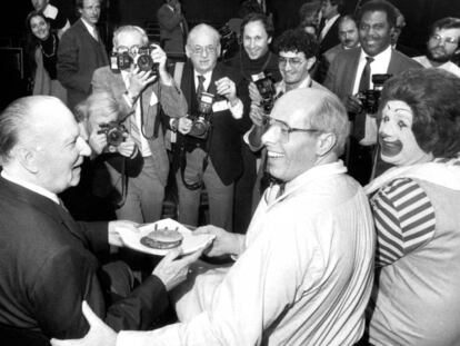 Foto tirada em 1984. O então presidente do McDonald's, Ed Rensi (centro), preparou para Richard McDonald (esquerda) o hambúrguer que levou a rede à marca de 50 milhões de sanduíches. O palhaço Ronald McDonald também participa da comemoração.