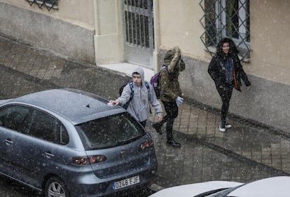 Un joven retira un poco de nieve de un coche en Madrid.