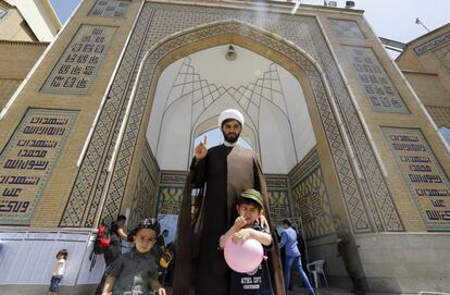 Un clérigo iraní posa con sus hijos tras votar en las urnas habilitadas en el lugar sagrado de Abdol Azim en la población de Shahre-Ray.