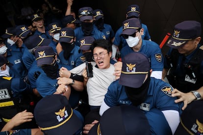 Agentes de policía detienen a uno de los manifestantes que han intentado entrar en la embajada japonesa en Seúl, este jueves.
