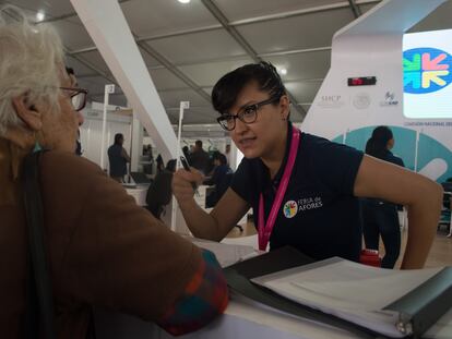 Una mujer de la tercera edad recibe recomendaciones de asesores financieros en una feria de Afores en Ciudad de México.