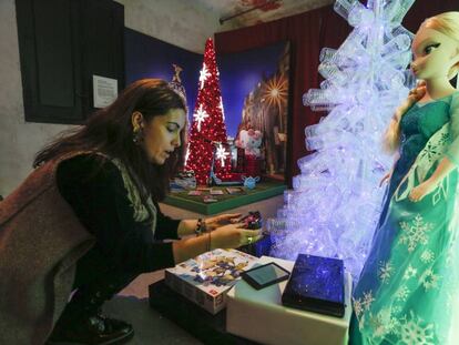 Una chica en la exposición junto al árbol de botellas de plástico inspirado en la década de 2010.