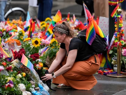 Una mujer lleva flores este domingo a la calle de Oslo donde ocurrió el tiroteo, en el centro de la capital noruega y junto a London Pub, local que es una referencia de la comunidad LGTBIQ+ desde los años setenta.