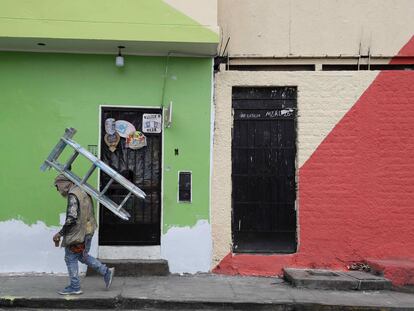 Un pintor de casas camina con una escalera mientras trabaja en las fachadas de la viviendas del cerro San Cristóbal, el 18 de Agosto de 2021, en Lima.